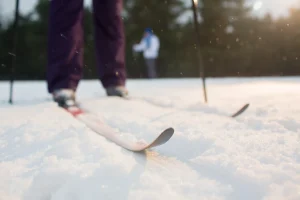 Primer plano de esquís sobre la nieve con un esquiador al fondo en ski indoor