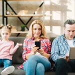 Niña enfadada porque sus padres no le prestan atención por culpa de la tecnología.