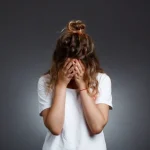 Mujer con las manos en el rostro, mostrando signos de ansiedad digital y estrés