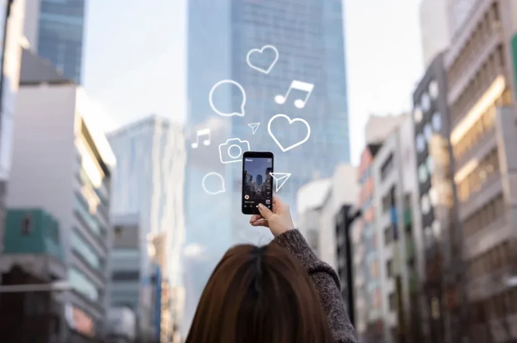 Persona usando un teléfono móvil en la ciudad mientras interactúa con íconos digitales flotantes representando redes sociales y medios.
