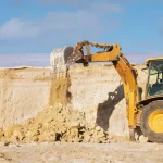 Retroexcavadora excavando y moviendo tierra en un terreno de construcción.