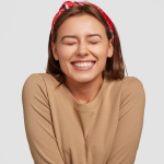 Mujer sonriendo felizmente después de recibir atención de odontología, mostrando su brillante sonrisa