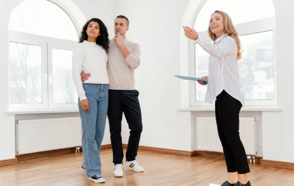 Agente inmobiliaria mostrando vivienda a pareja interesada en vender piso en internet o comprar
