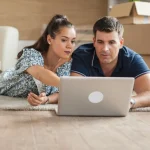 Pareja consultando un portátil para vender piso en internet desde casa