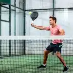 Jugador de pádel realizando un saque en pista indoor durante un partido