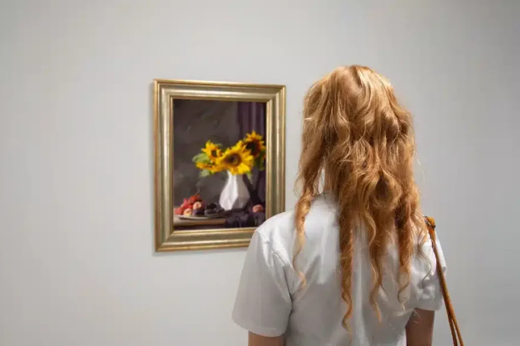 Persona observando un cuadro de girasoles en una galería de arte