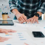 Equipo de trabajo planificando una estrategia empresarial con gráficos y documentos sobre la mesa.