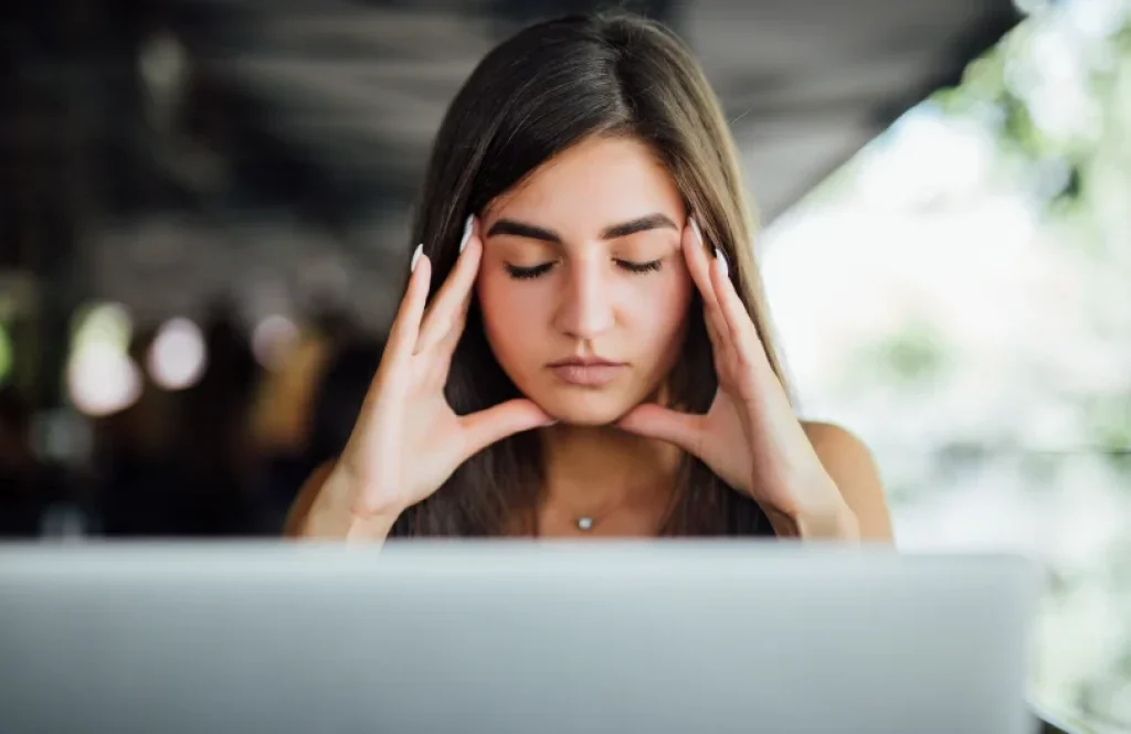 Mujer con estrés digital frente al ordenador buscando recuperar la calma y concentración