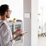 Hombre controlando un panel de domótica desde el móvil en una vivienda de alquiler turístico