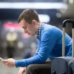Hombre consultando el móvil en el aeropuerto para reclamar un vuelo retrasado